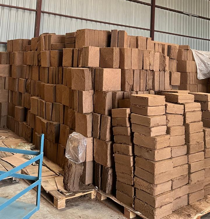 Hundreds of stacked, ready-to-export coco peat blocks in warehouse storage.